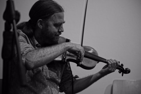 Gabriel McCaslin playing the violin contemplatively.